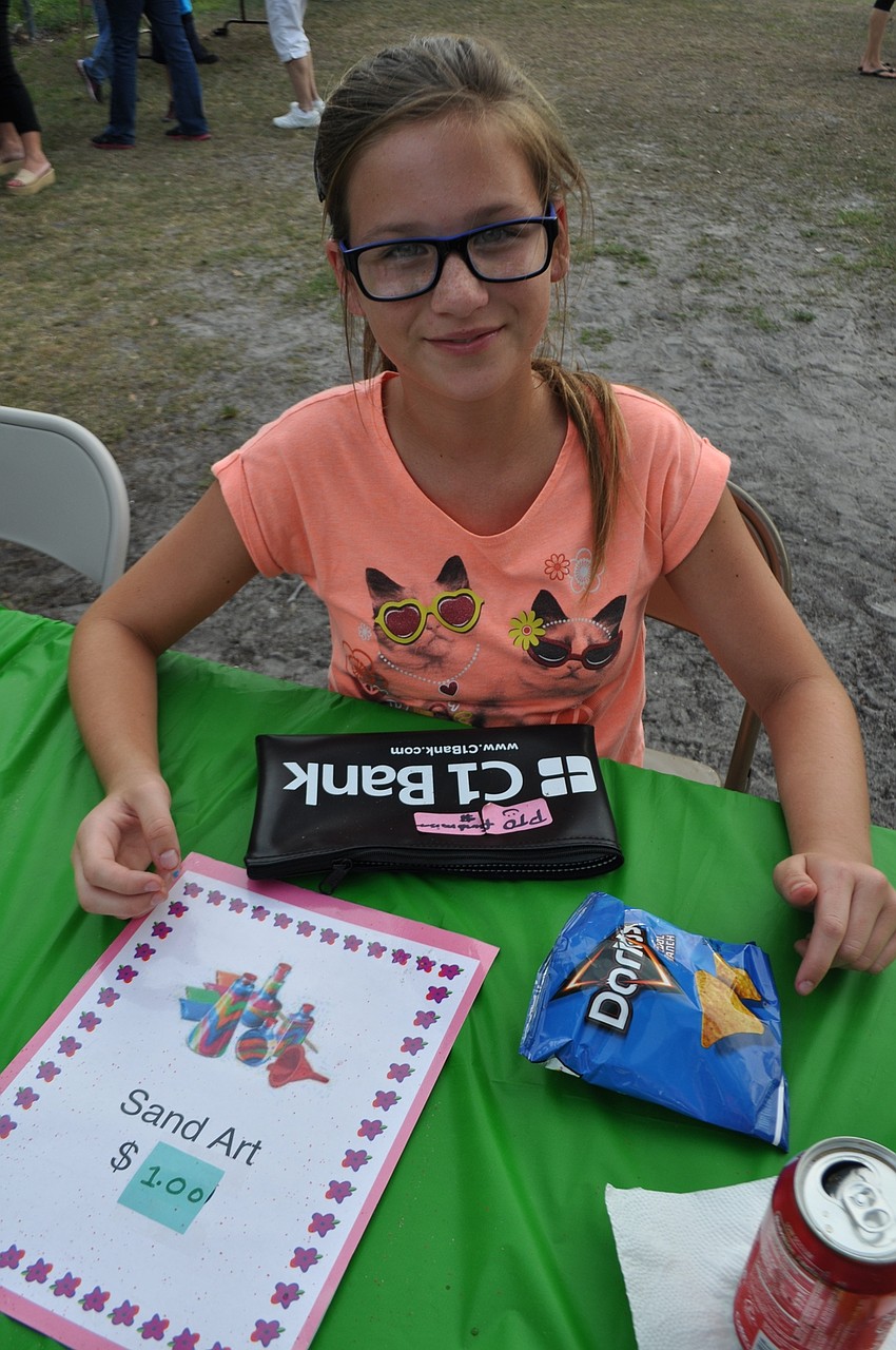 Braden River Middle School student Makenna Stennett runs the sand art craft booth.