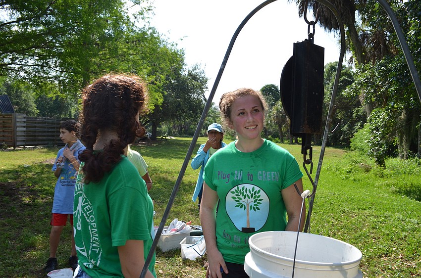 Minnah Stein and Emma Kanego weigh a bucket of air potatoes they collected.