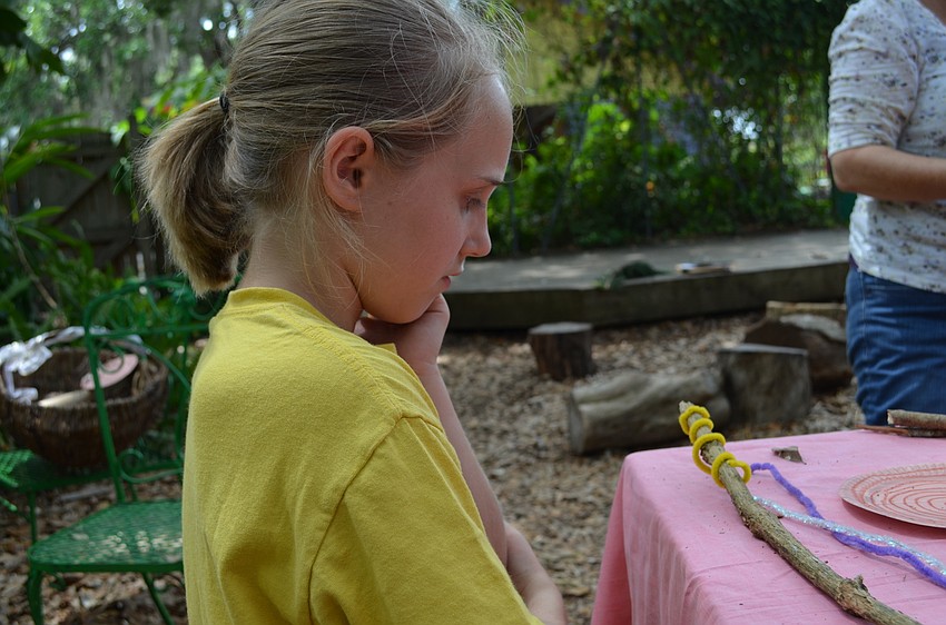Amanda Beall decorates a talking stick.