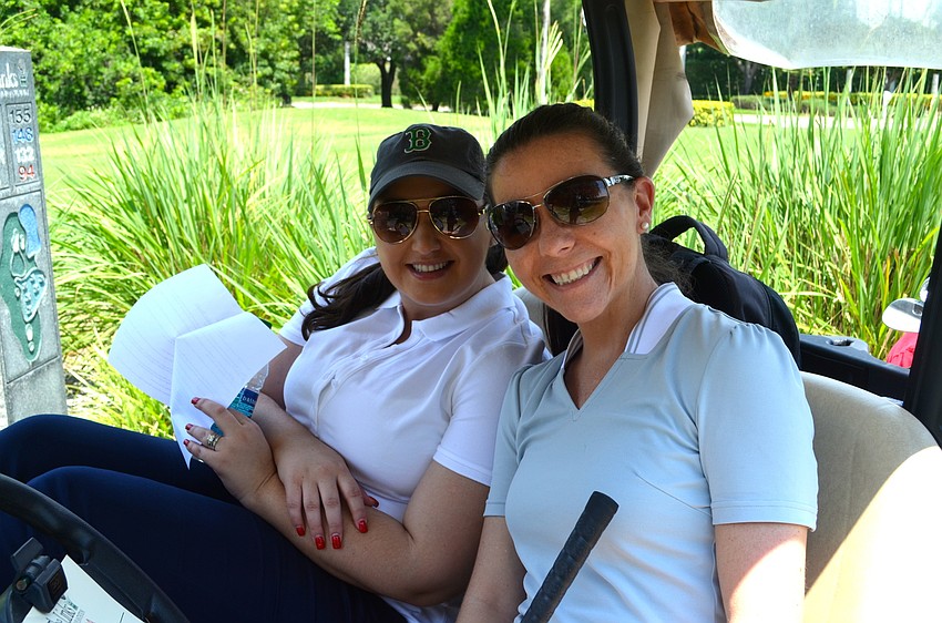 Toni Clarke and Katie Kawcak relax under the shade of their golf cart.