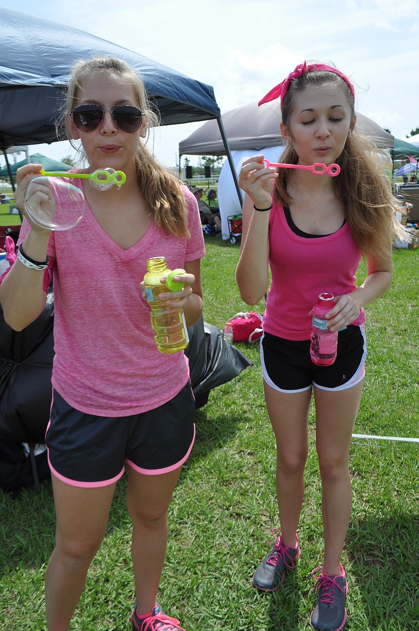 Braden River Middle School’s Harley Kovalick and Hayley Veltri blow bubbles at walkers.