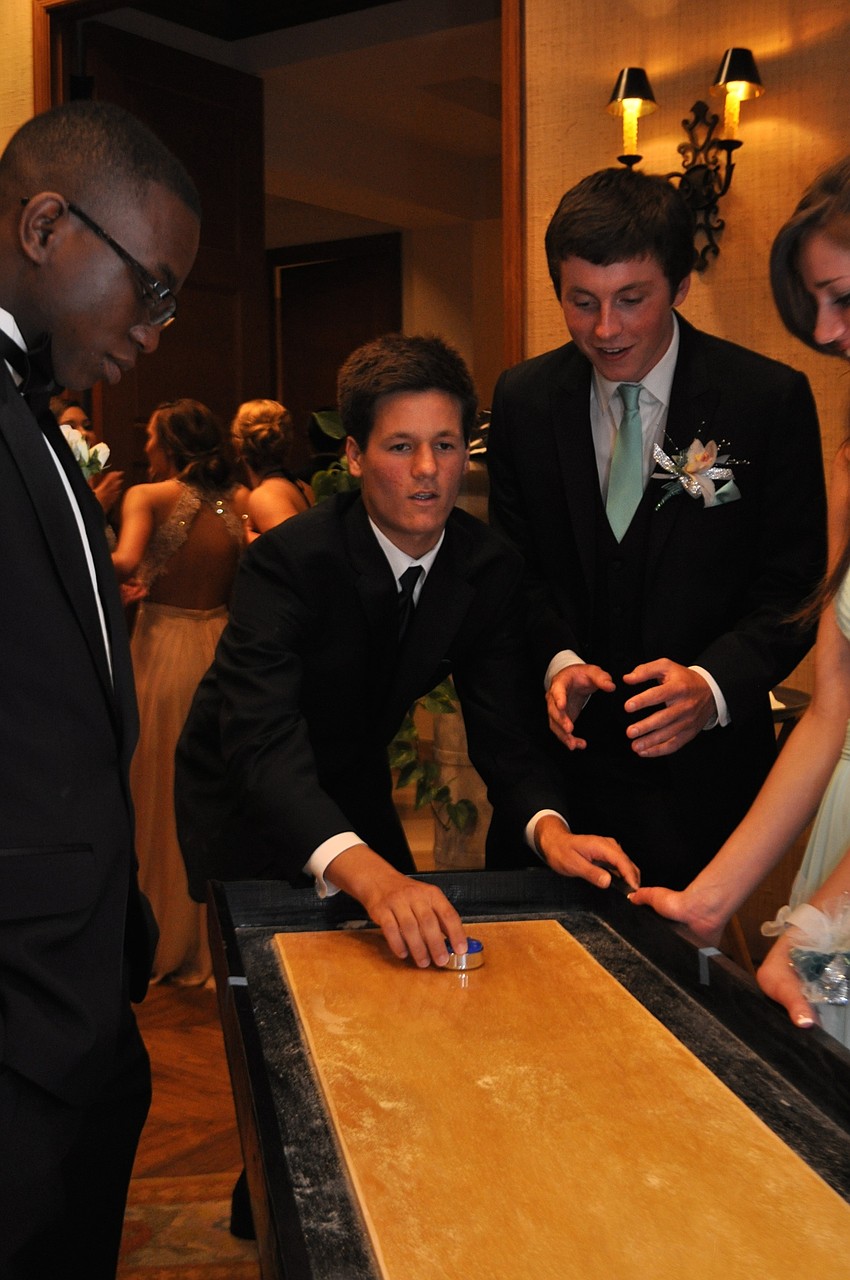 Will Harwell takes aim in a game of shuffleboard against friend Vaughn Garcia, right, as friend Zach Schandorf-Lartey, left, watches.