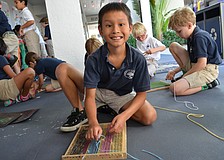 In the courtyard breezeway students weave yarn on a loom.
