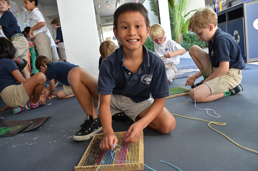 In the courtyard breezeway students weave yarn on a loom.