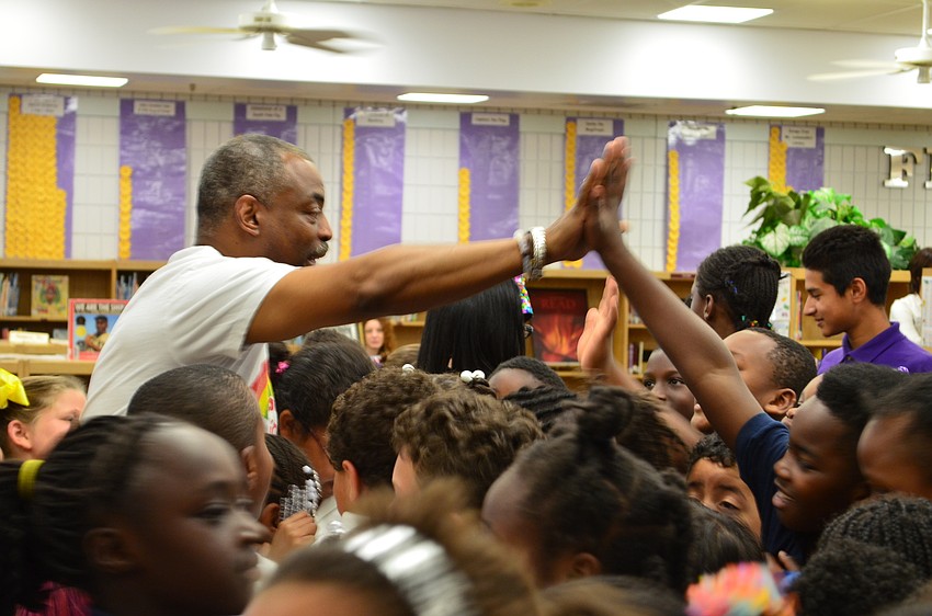In a crowd of students LeVar Burton responds to a high-five.