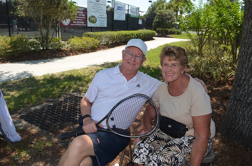 Wade and Joan Wilkerson watch a tennis match from the shaded sidelines.