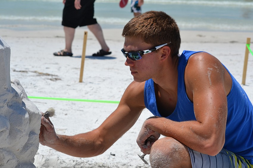 Justin Muklewicz brushes sand off of his sculpture.