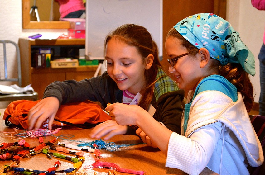 Rachel Cox and Justyce Rulison work together to make a bracelet.