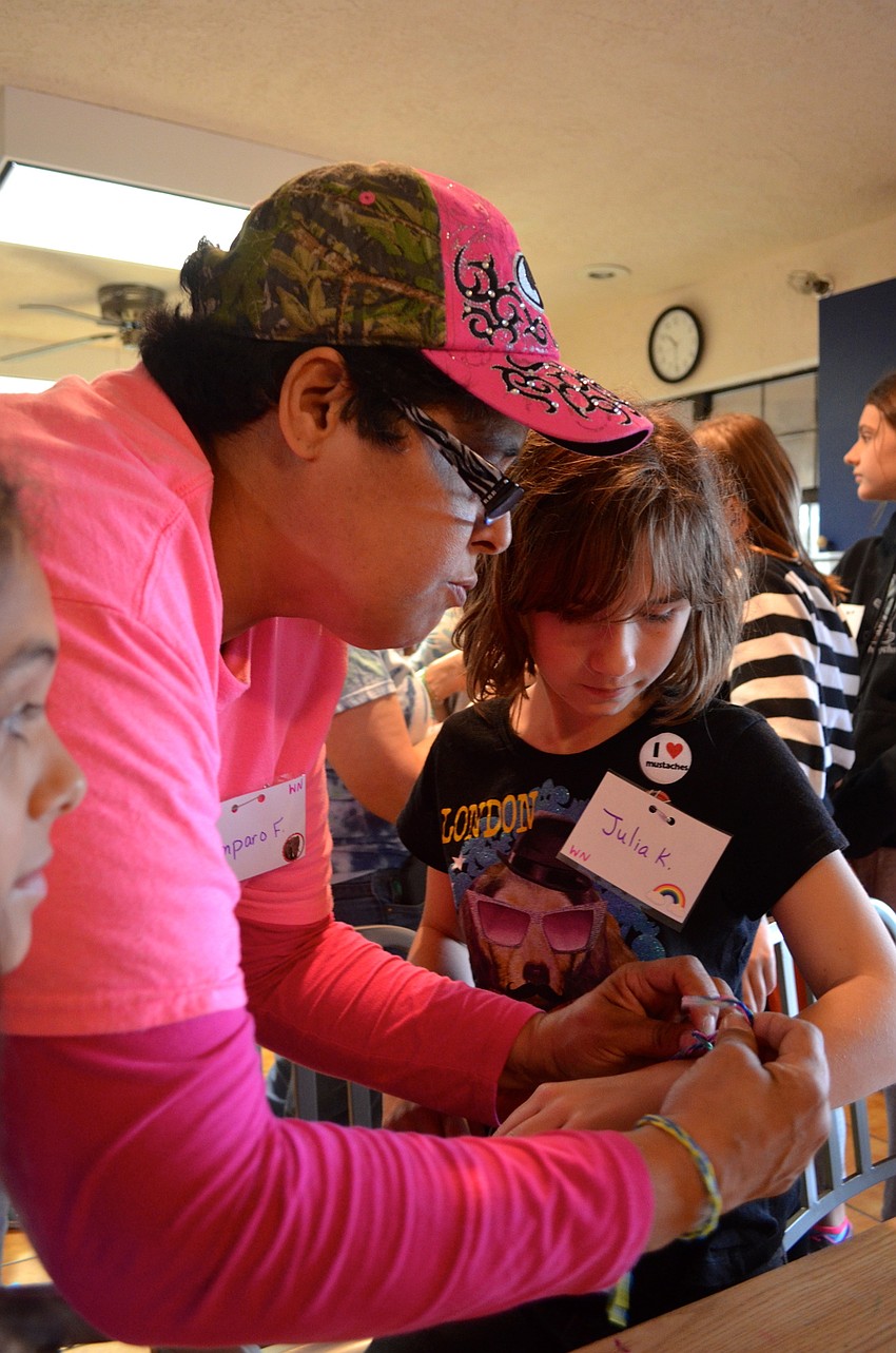 Volunteer Amparo Frias helps Julia Kazwell fasten her bracelet.