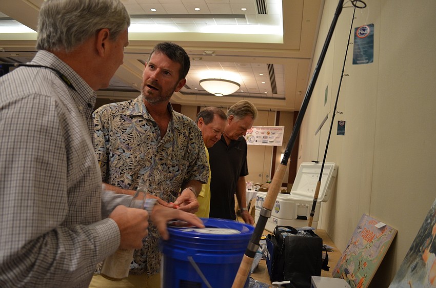 Jim Milner and Aron Johnson place their tickets in the raffle that will be award at the banquet in July.