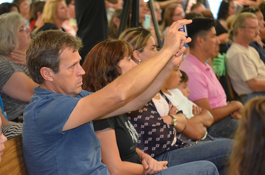 Proud parent Pavlin Kioutchoukov records his child's performance on stage.