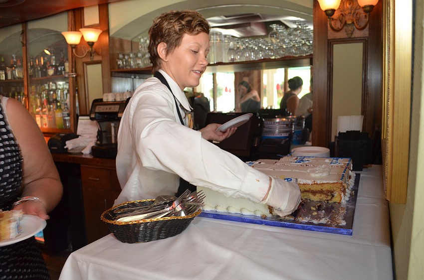 Kalin Delfino serves pieces of the birthday cake to celebrate the 100th anniversary of Kiwanis International.