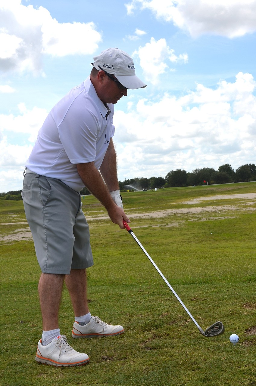 Scott Waller focuses on the ball before swinging on the driving range.
