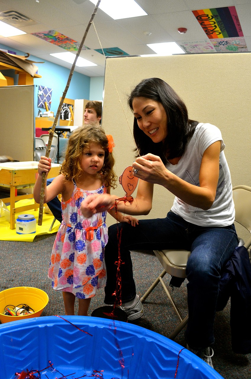 Hadley Hastreiter catches a faux fish with the help of event volunteer June Seidl.
