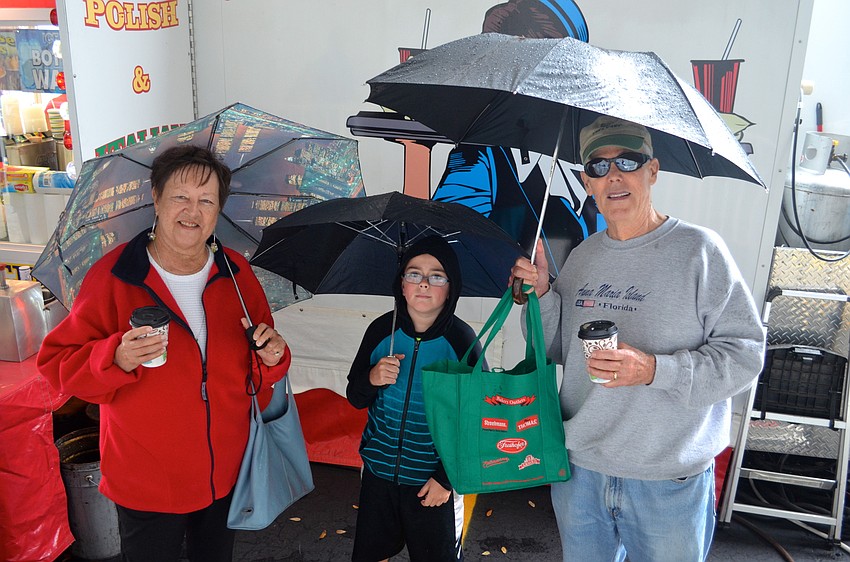 Ann, Connor and Bernie Casey find cover from the rain under their umbrellas.