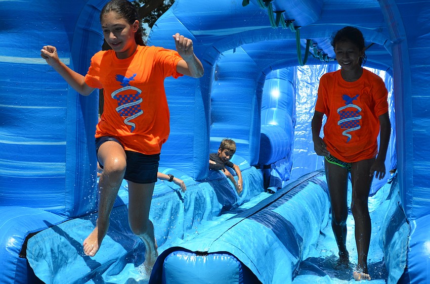 Emma Helfrich and Maya Lopez finish their turn on the water slide with a jump in the landing pool.