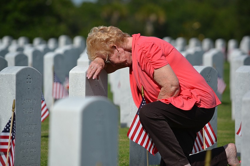 Janice Myers takes a moment at the gravesite for her husband Henry at the Sarasota National Cemetery.