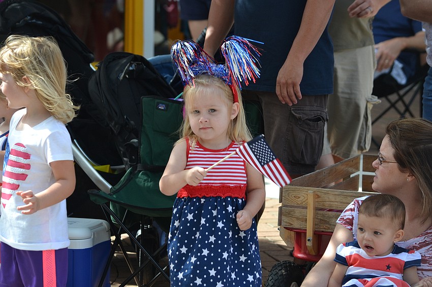 Isabella Carberry waves her flag as Sarasota Police officers walk by.