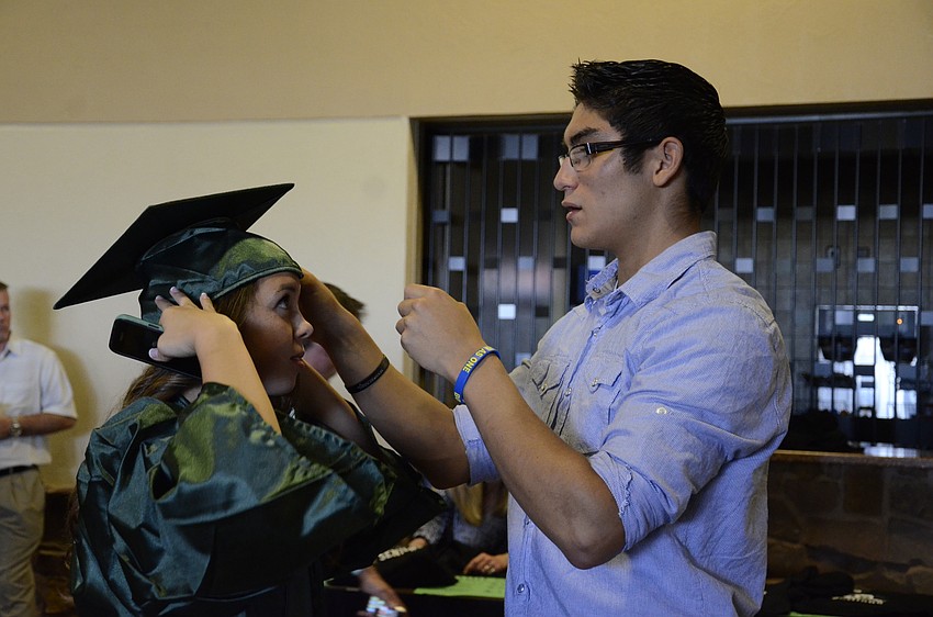 Albert Orozeo helps his girlfriend, Elizabeth Belan, with her cap.