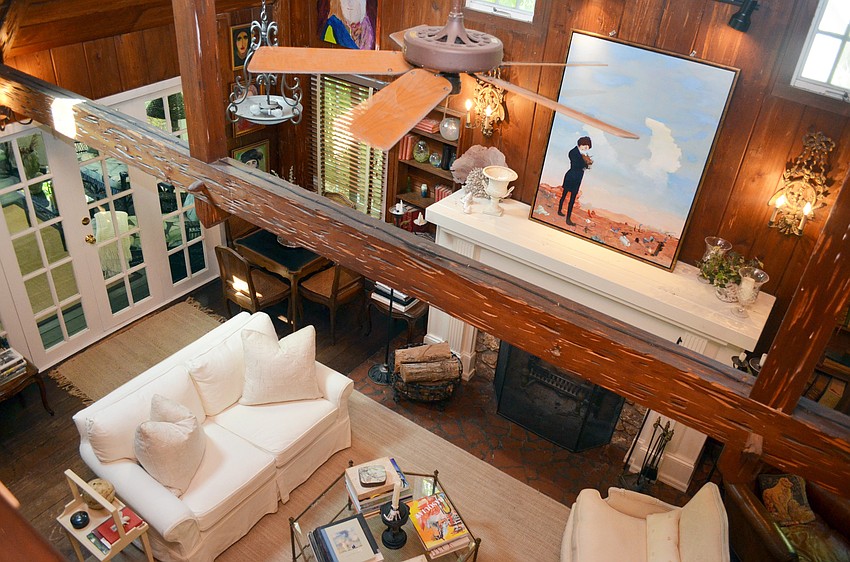 The front door opens to a surprising “wow factor:” a two-story living room, completely paneled in pecky cypress, with a single, rough-hewed beam and a massive stone fireplace.