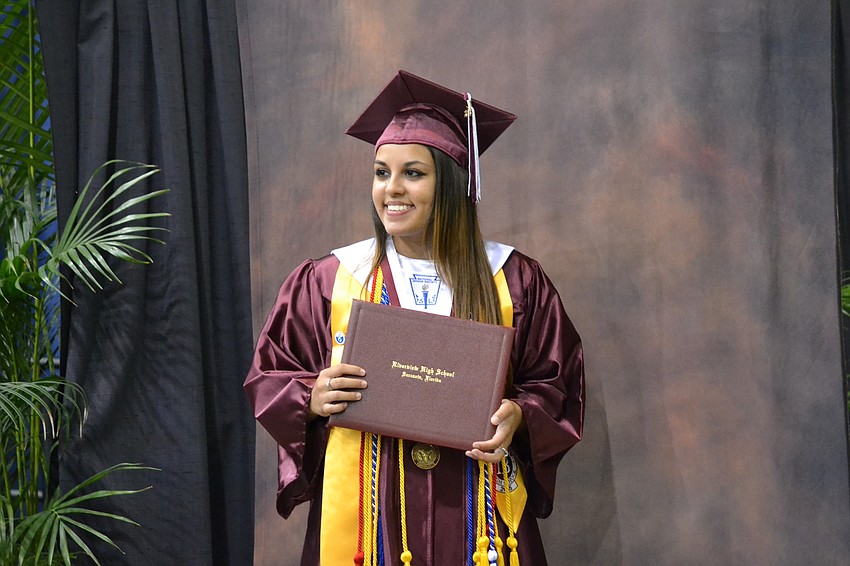 Astrid Arias poses for a photo after receiving her diploma on stage.