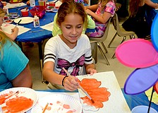 Leila Madrid finishes painting an orange flower.