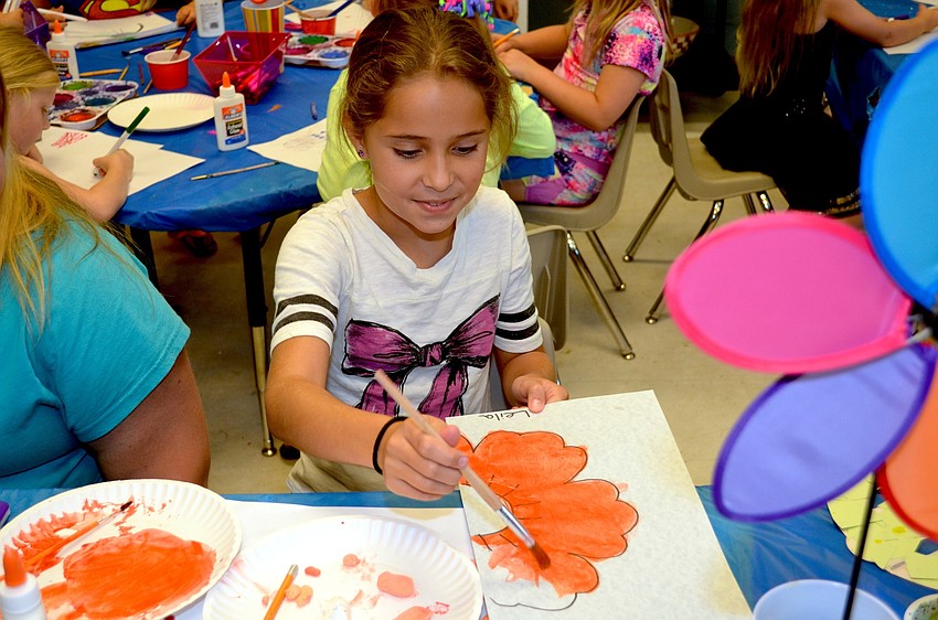 Leila Madrid finishes painting an orange flower.