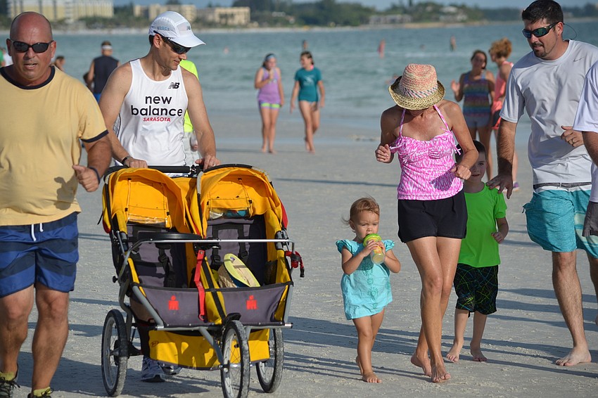 Lyla Ochsendorf runs with her parents during the Siesta Summer Beach Run.