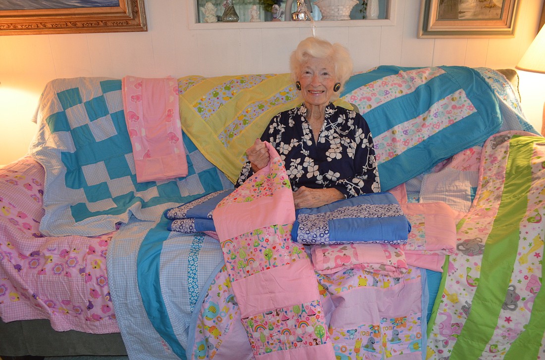 Dorothy Wallace Foisy with several of her quilts, which will be donated to local children in need.