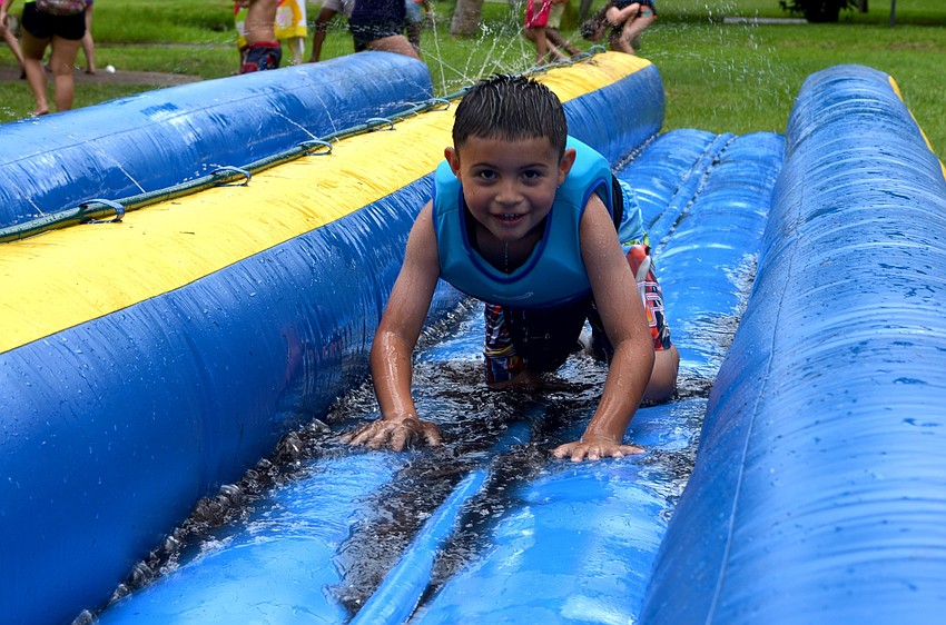 Josiah Valdez crawls down an inflatable water slide.