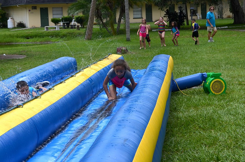 Cienna Paredes races down the slide toward a shallow pool of water.