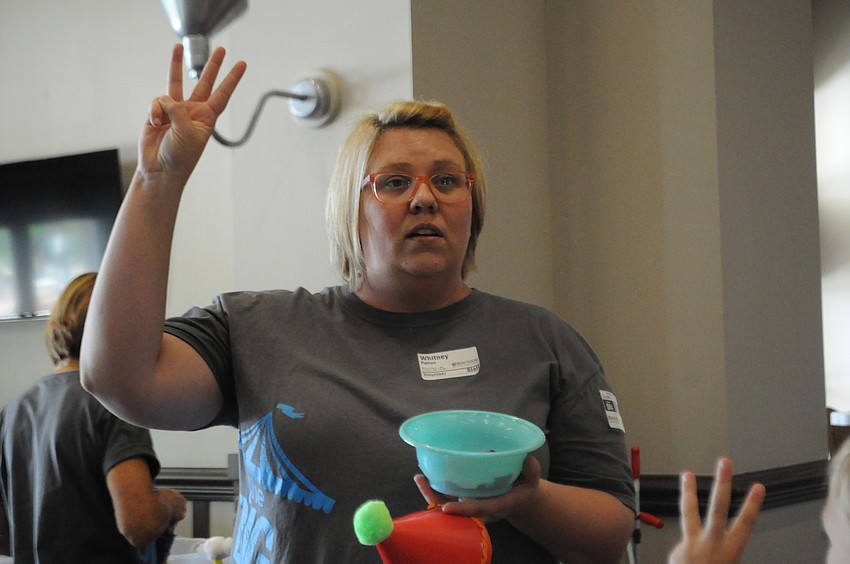 Volunteer Whitney Patton explains the hat craft to the children.