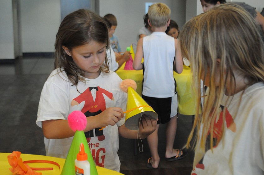 Jessica Mowrey, 6, helps Claire Van Nortwick, 7, glue a ribbon on her hat.
