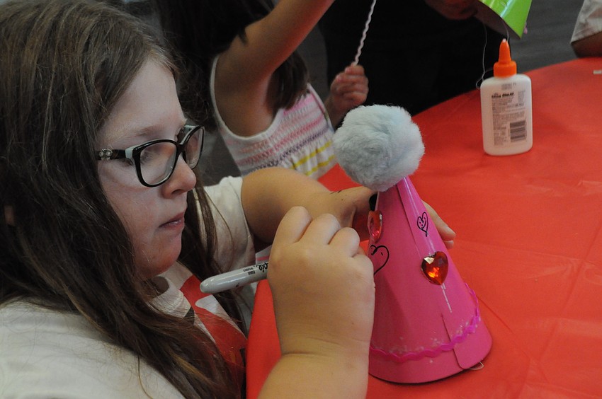 Bella Barone, 7, puts the finishing touches on her hat.