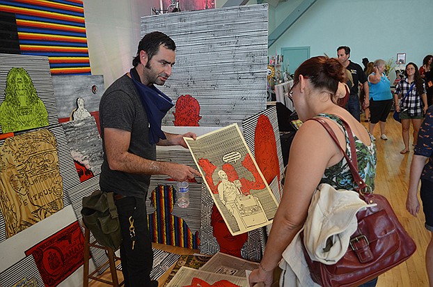 John Lichtenstein shows a customer some of his prints.