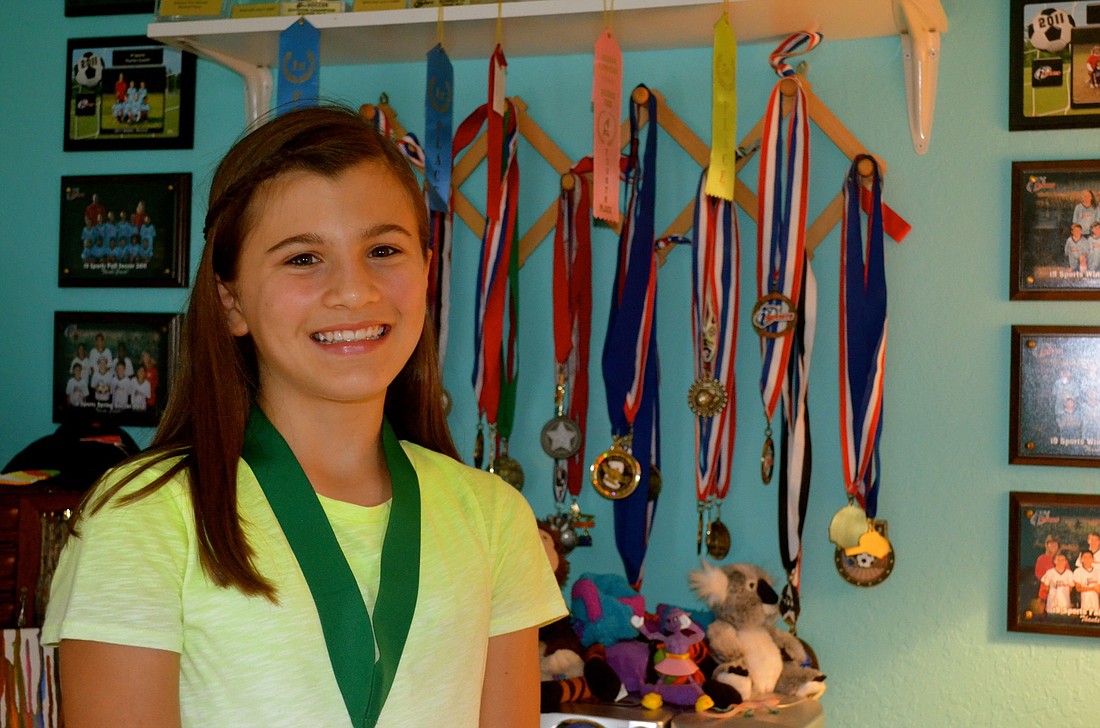 Hannah Arduini shows off her wall of medals from science fairs, soccer, tae kwon do and other activities in which she is involved.