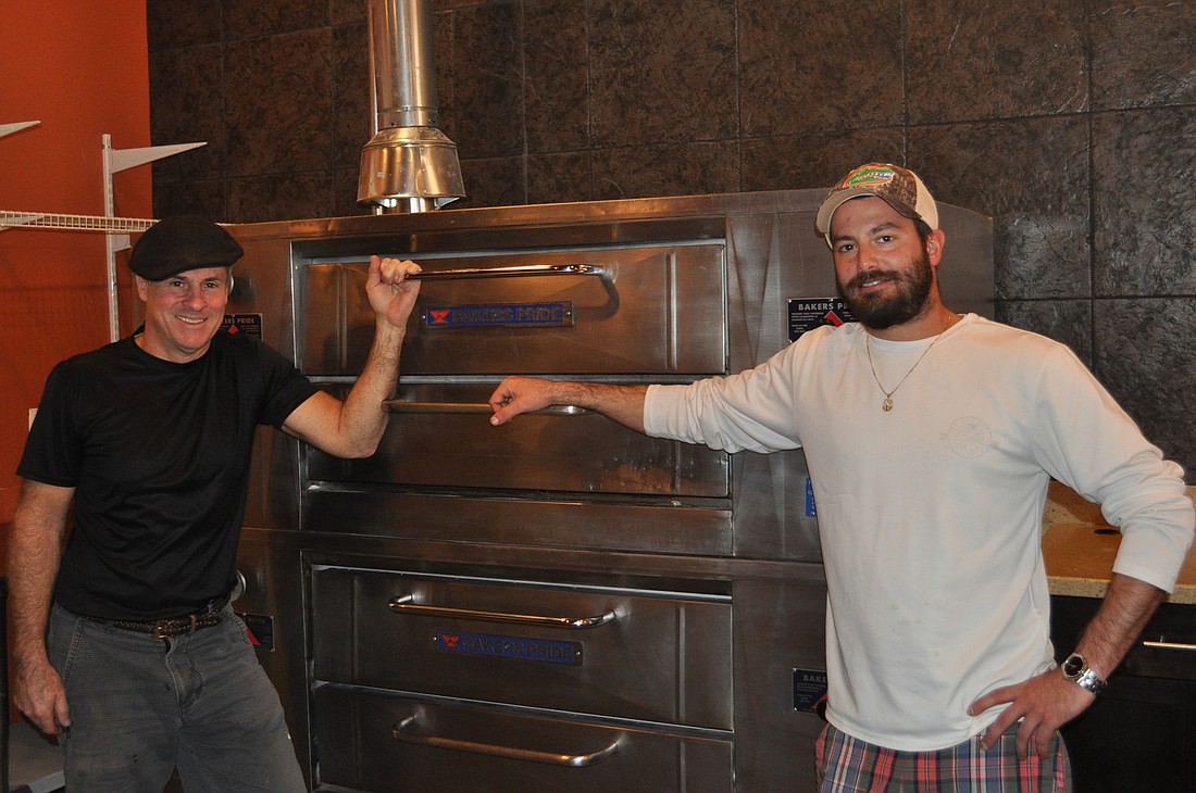 Owner Glenn Comeau, left, and General Manager Brian Izzo stand in front of the pizza oven at Flatbread on Main. The restaurant is slated to open within a week.