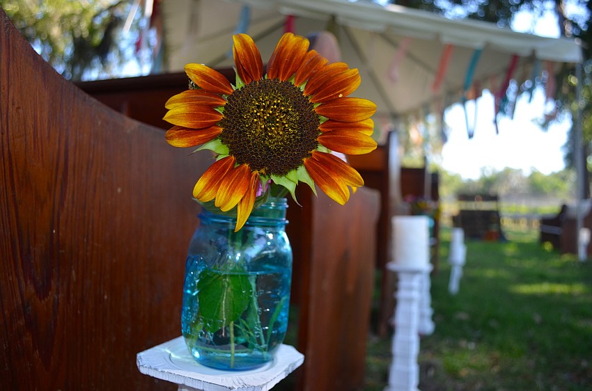 Flowers in Mason jars cover tables and the outdoor event areas.