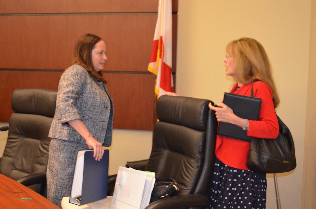 Town Attorney Maggie Mooney-Portale chats with Commissioner Lynn Larson after her resignation Monday.