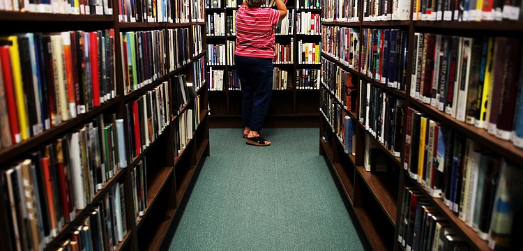 Carol Koplik shelves books on June 10, at the Longboat Library.