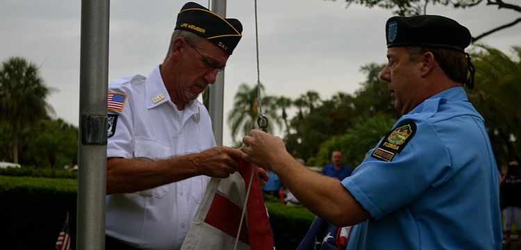 Roger DeWitt and John Raber, both members of Disabled American Veterans Chapter 18, prepare to raise the flag.