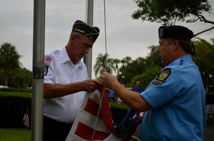 Roger DeWitt and John Raber, both members of Disabled American Veterans Chapter 18, prepare to raise the flag.