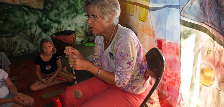 Jan Dahlstrom shows the children how to create a necklace from clay and string.