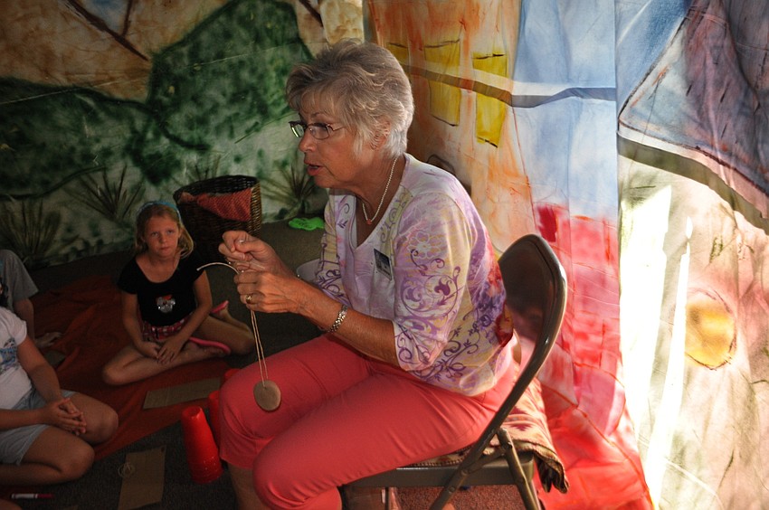Jan Dahlstrom shows the children how to create a necklace from clay and string.