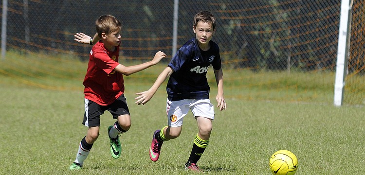 Twelve-year-olds Calvin Drake and Jacob Jordan race toward the ball during a shooting drill.