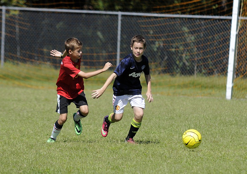 Twelve-year-olds Calvin Drake and Jacob Jordan race toward the ball during a shooting drill.