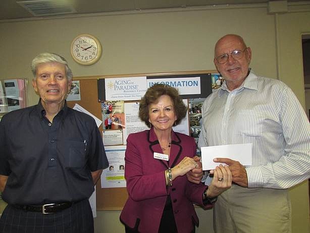 Dick Pelton, co-chair, and Donna Dunio, executive director for Aging in Paradise Resource Center, accept a $4,000 donation from local supporter, Arnold Simonsen.