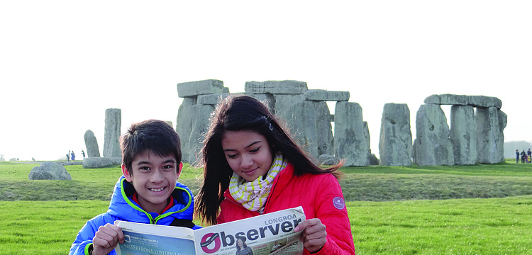 MONUMENTAL MOMENT. Alex Kumar, 12, and Madelyn Kumar, 15, catch up on their Observer news while visiting one of the worldâ€™s biggest mysteries â€” Stonehenge â€” in Wiltshire, England.