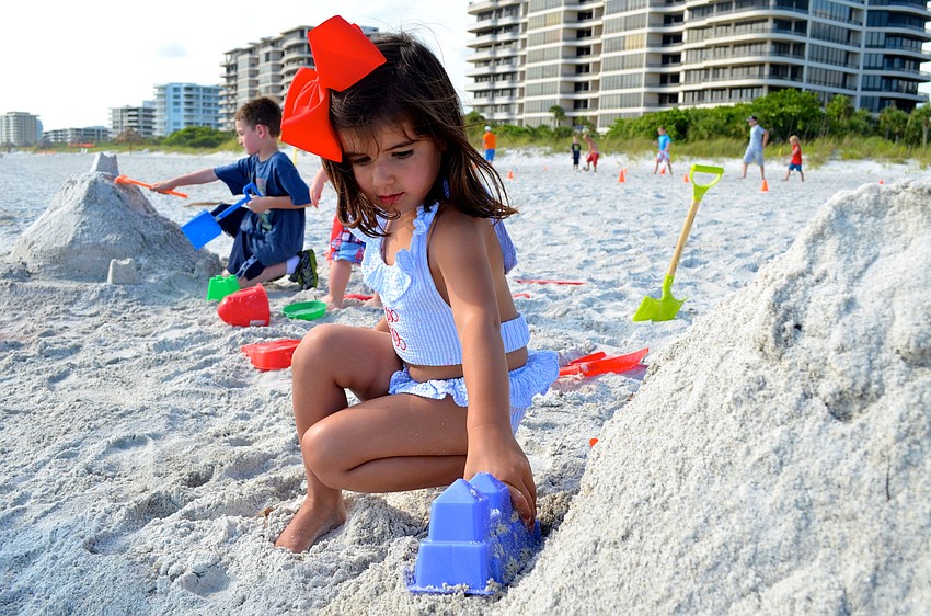 Caroline Moreno plays with sand on the beach.