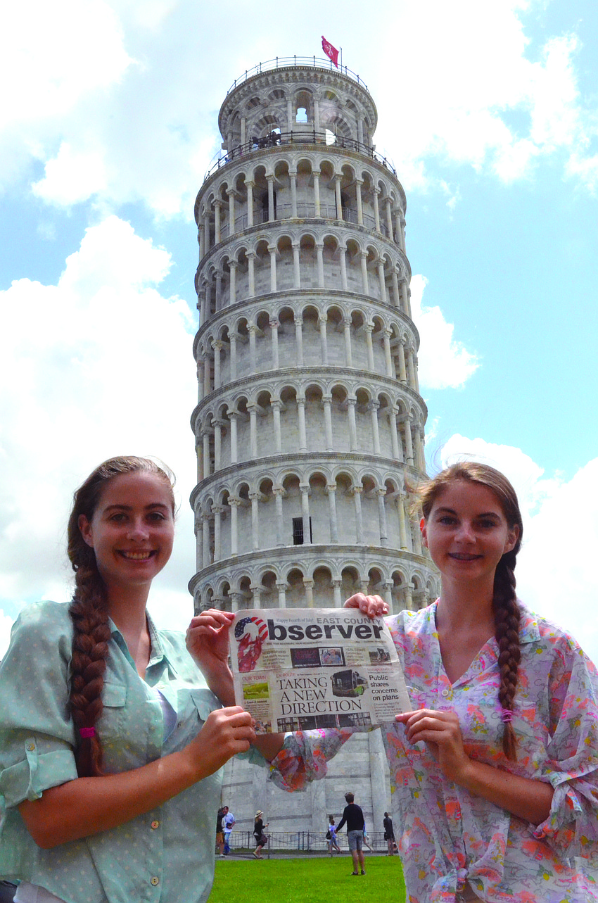 SISTER, SISTER. Emily and Caitlin Camire catch up on their East County Observer news before climbing more than 290 stairs to the top of the Leaning Tower of Pisa, in Italy.
